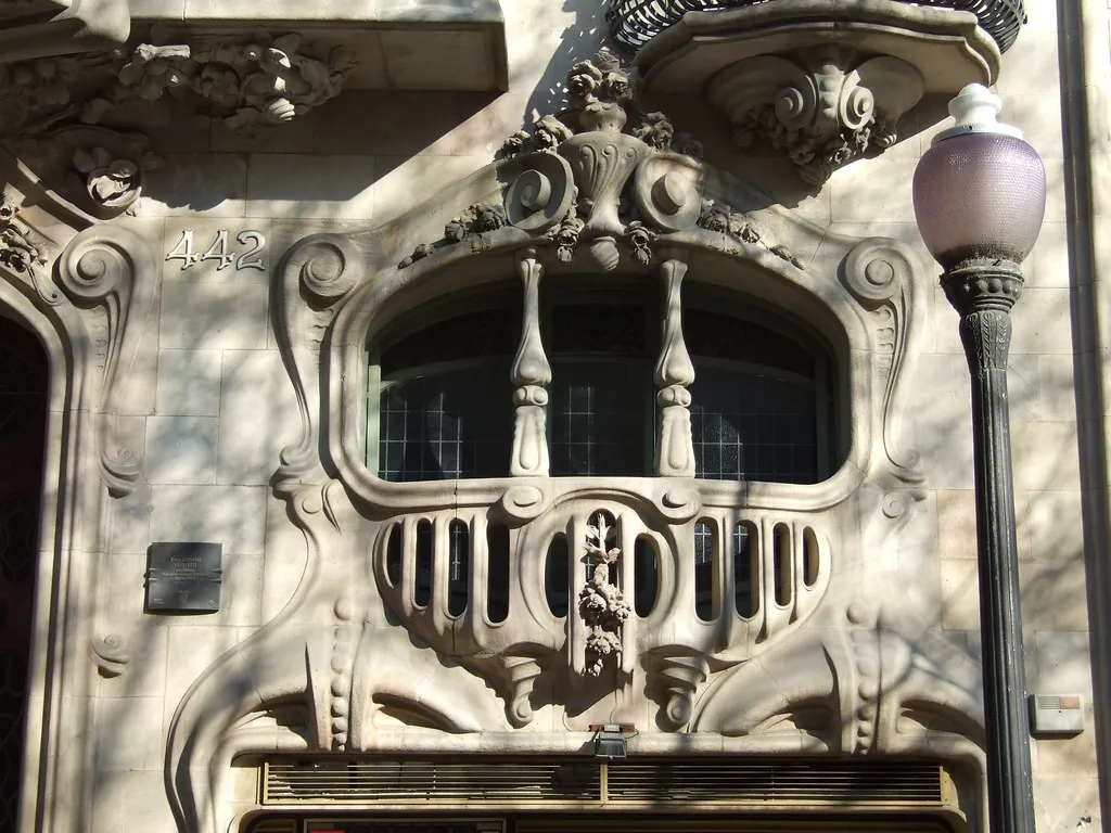 Balcón modernista con relieves de piedra y una farola