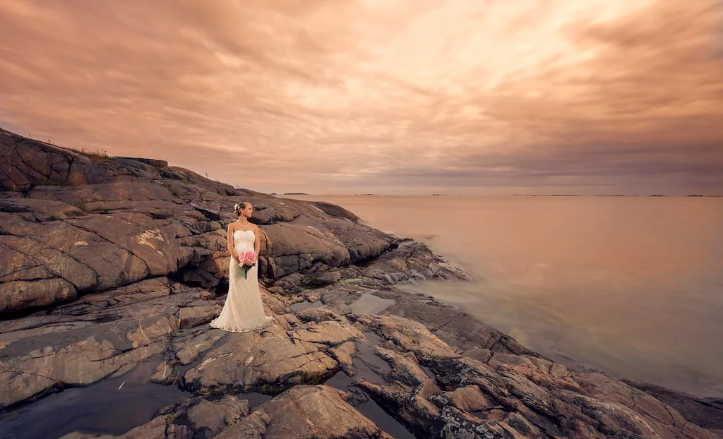 Novia sobre rocas junto al mar al atardecer