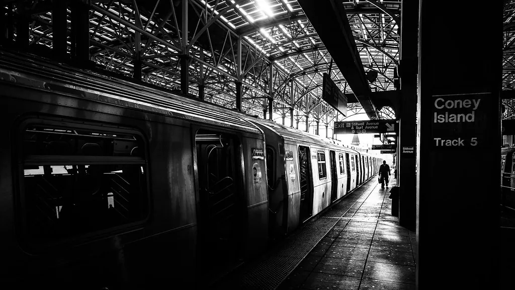 Andén de metro con un tren detenido en blanco y negro