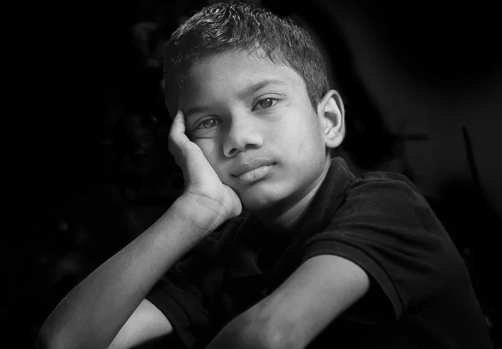 Niño apoyado en su mano mirando a cámara